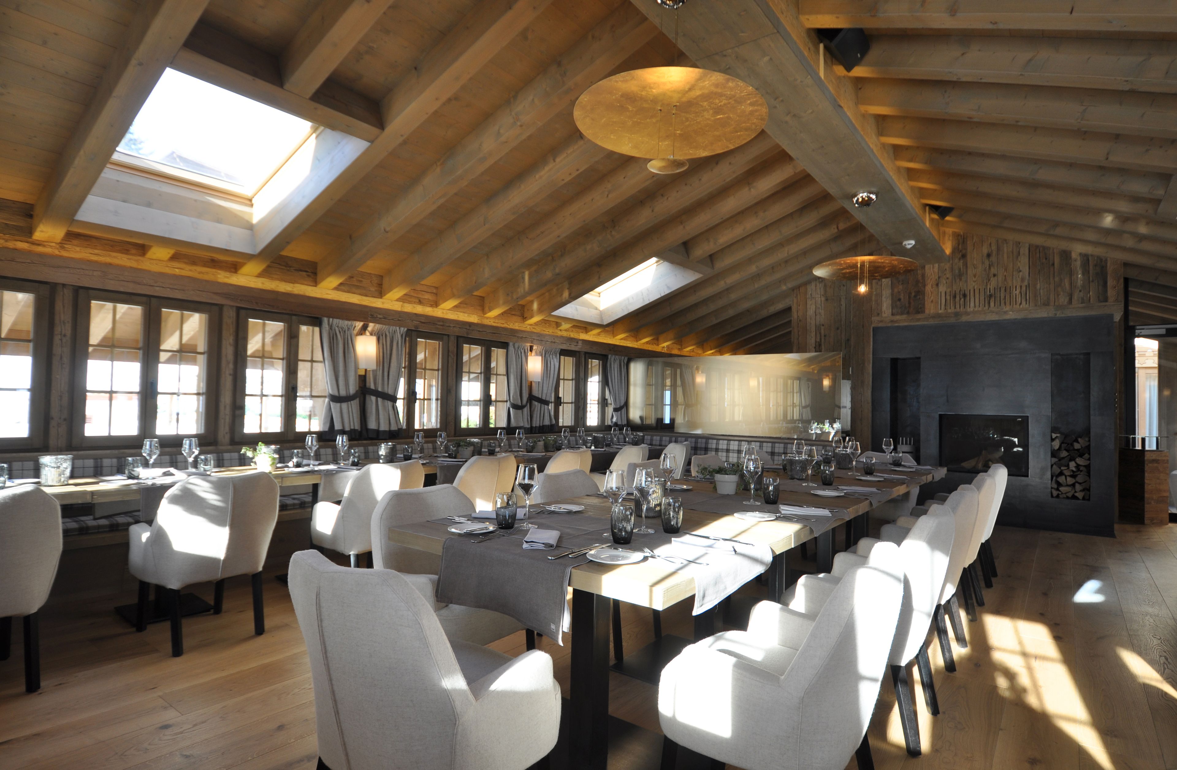 A large dining area with high ceilings and skylights, wooden beams, and a fireplace.