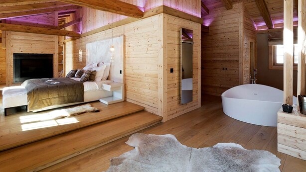 A log cabin interior with a bed, a bathroom, and a large window. - Hotel de Rougemont & Spa (Rougemont)
