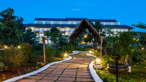 A pathway leading to a building with a reception area, surrounded by greenery and decorative lighting. - Amata Garden Resort (Nyaungshwe)