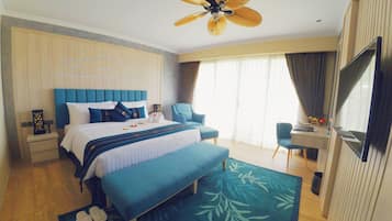 A hotel room with a bed, a desk, a chair, a TV, and a ceiling fan.