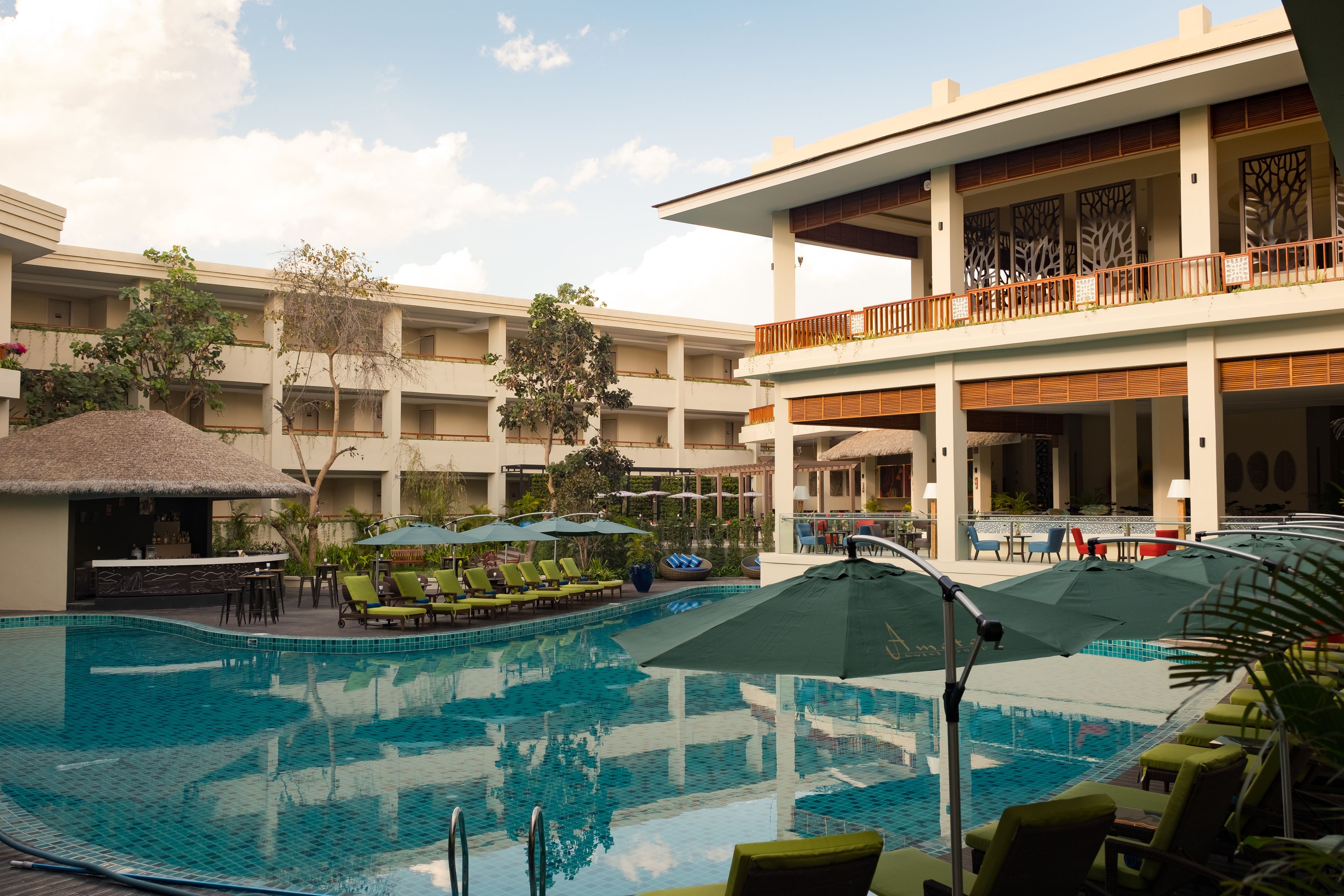 A hotel pool area with lounge chairs, umbrellas, and a bar.