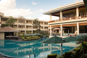 Uma área de piscina de hotel com espreguiçadeiras, guarda-sóis e um bar.