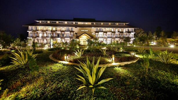 A multi-story hotel with a symmetrical facade, illuminated windows, and a central entrance. - Amata Garden Resort (Nyaungshwe)