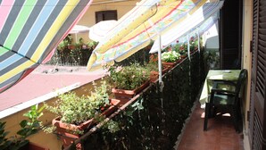 A terrace with potted plants, a table, and a chair. - Legend R. G. (Rome)