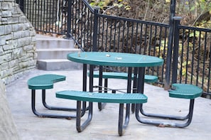 Outdoor picnic tables sit adjacent to a stone wall and staircase.