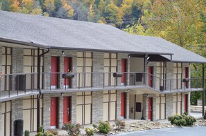 Traditional two-story motel with stone and wood paneling, featuring balconies and red accents.