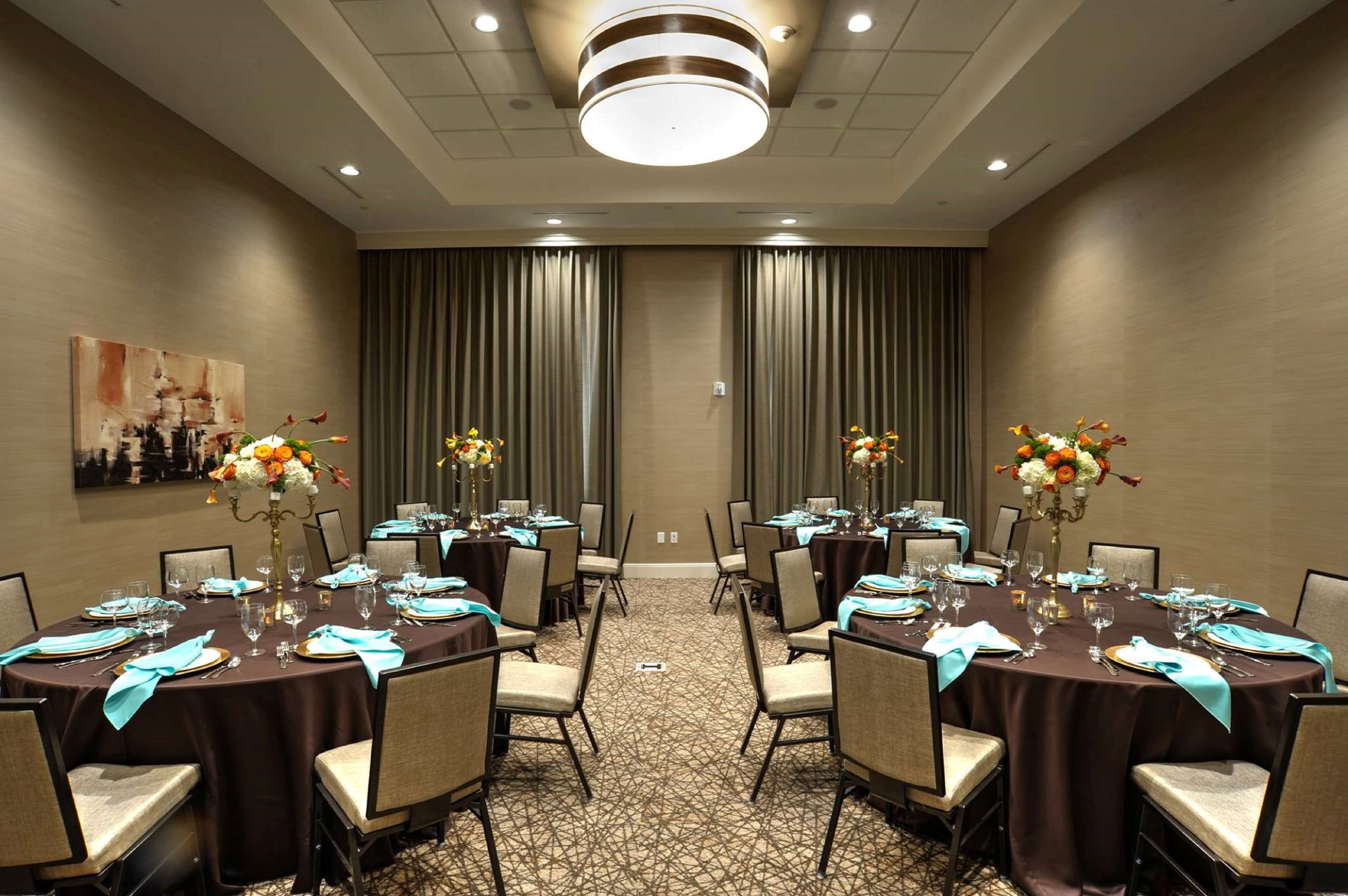 A conference room with round tables, chairs, and floral centerpieces.