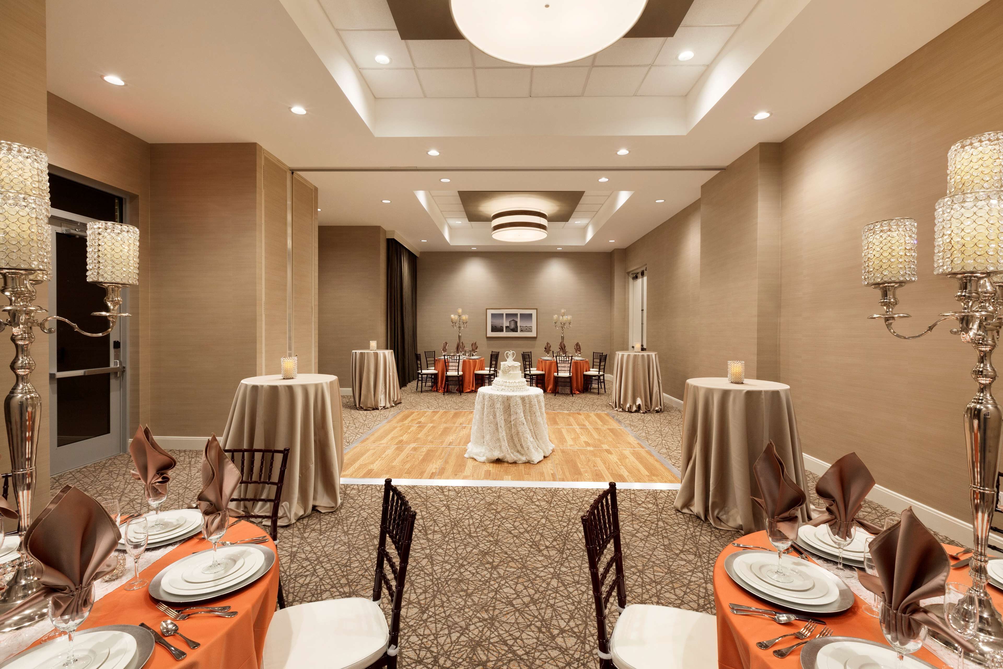 A banquet hall with round tables, chairs, and a central dance floor.