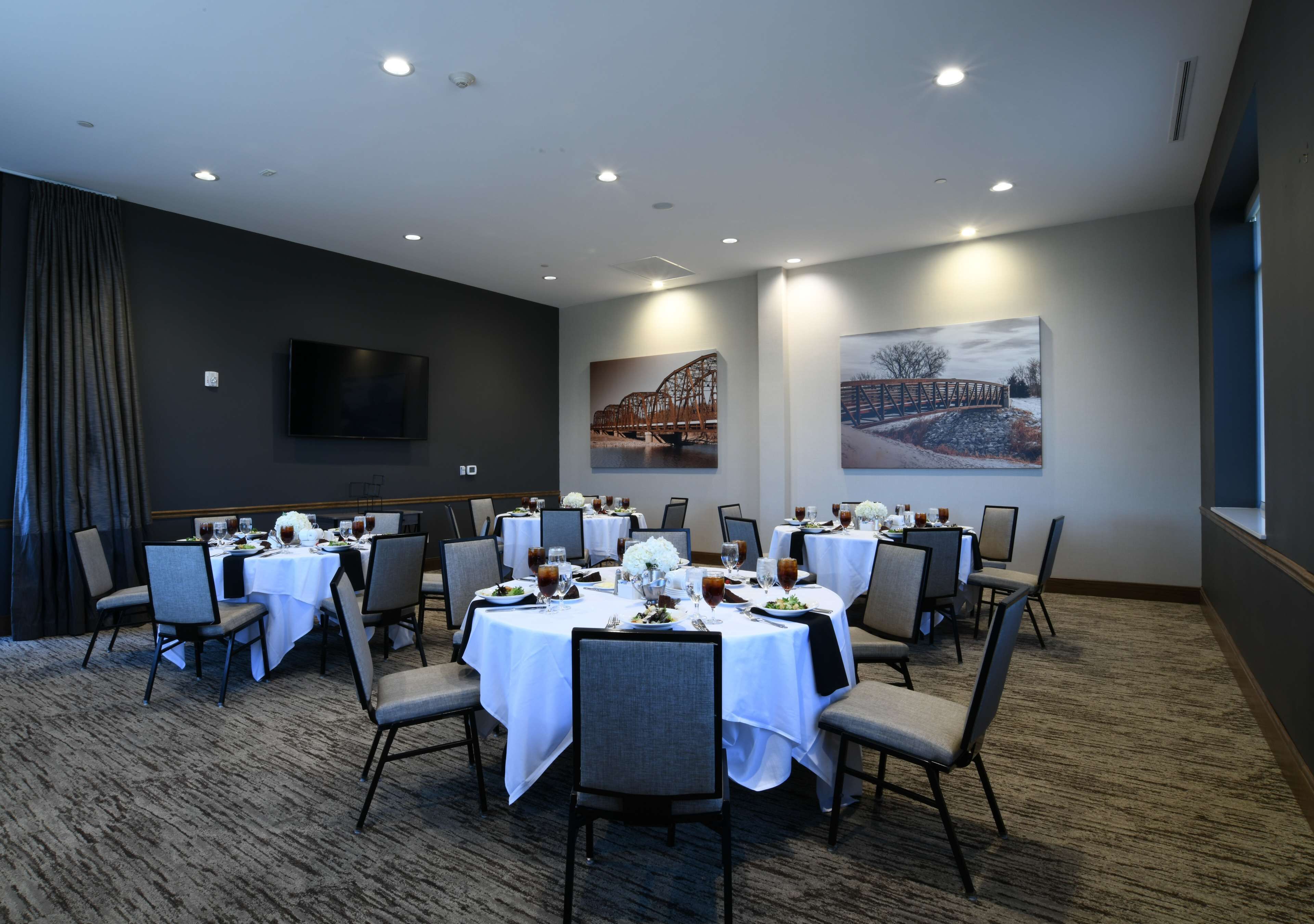 A conference room with multiple tables set for dining, equipped with chairs and table settings.