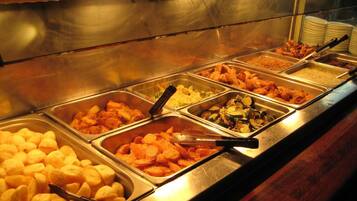 A buffet with various food items in metal serving trays.