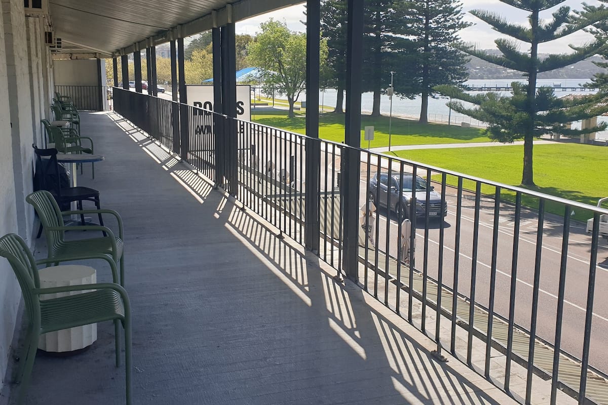 Ein Balkon mit grünen Stühlen und Blick auf einen Parkplatz und Grünflächen.