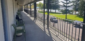 A balcony with green chairs and a view of a parking lot and greenery. - Grand Tasman Hotel (Port Lincoln)