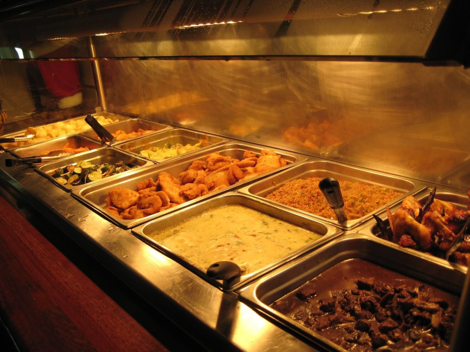 Un bufé con diversas opciones de comida, incluyendo frituras, platos de arroz y carne.