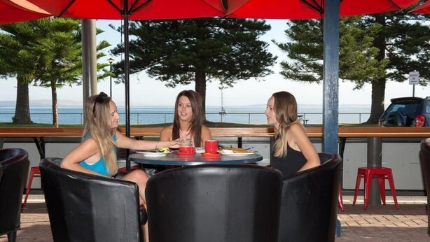 Three people seated at a round table with a view of the sea. - Grand Tasman Hotel (Port Lincoln)