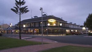 A two-story building with a flat roof and a corner entrance. There are multiple windows on the ground floor, and a small parking area is visible in front. - Grand Tasman Hotel (Port Lincoln)