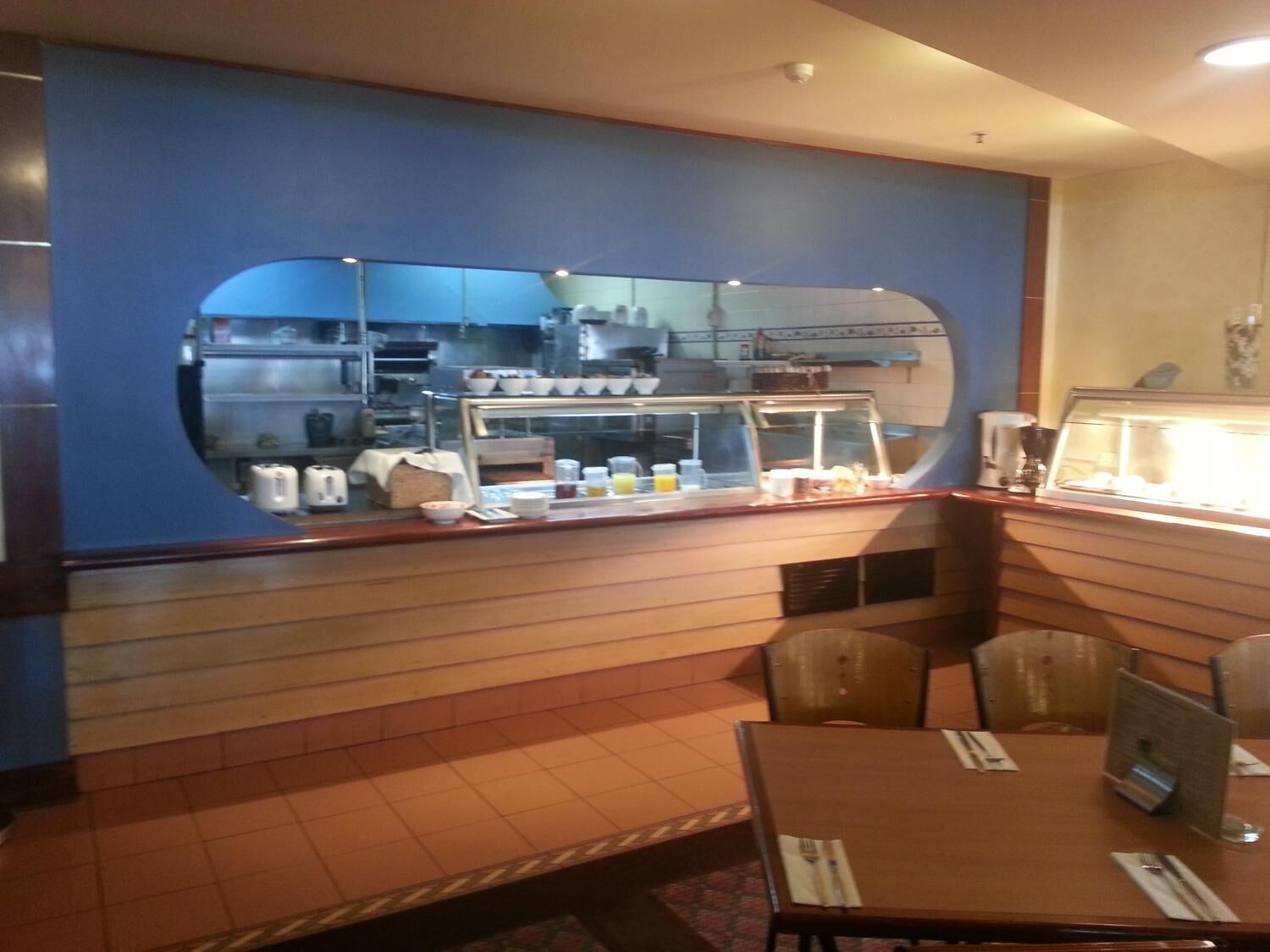 Un restaurante con mostrador, sillas y un atril para el menú.