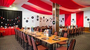 A conference room with long tables, red curtains, and wall decorations including vinyl records. - Grand Tasman Hotel (Port Lincoln)