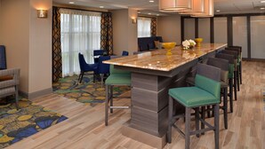 A hotel lobby with a central bar area, seating arrangements, and a patterned carpet. - Hampton Inn Broussard-Lafayette Area (Broussard)