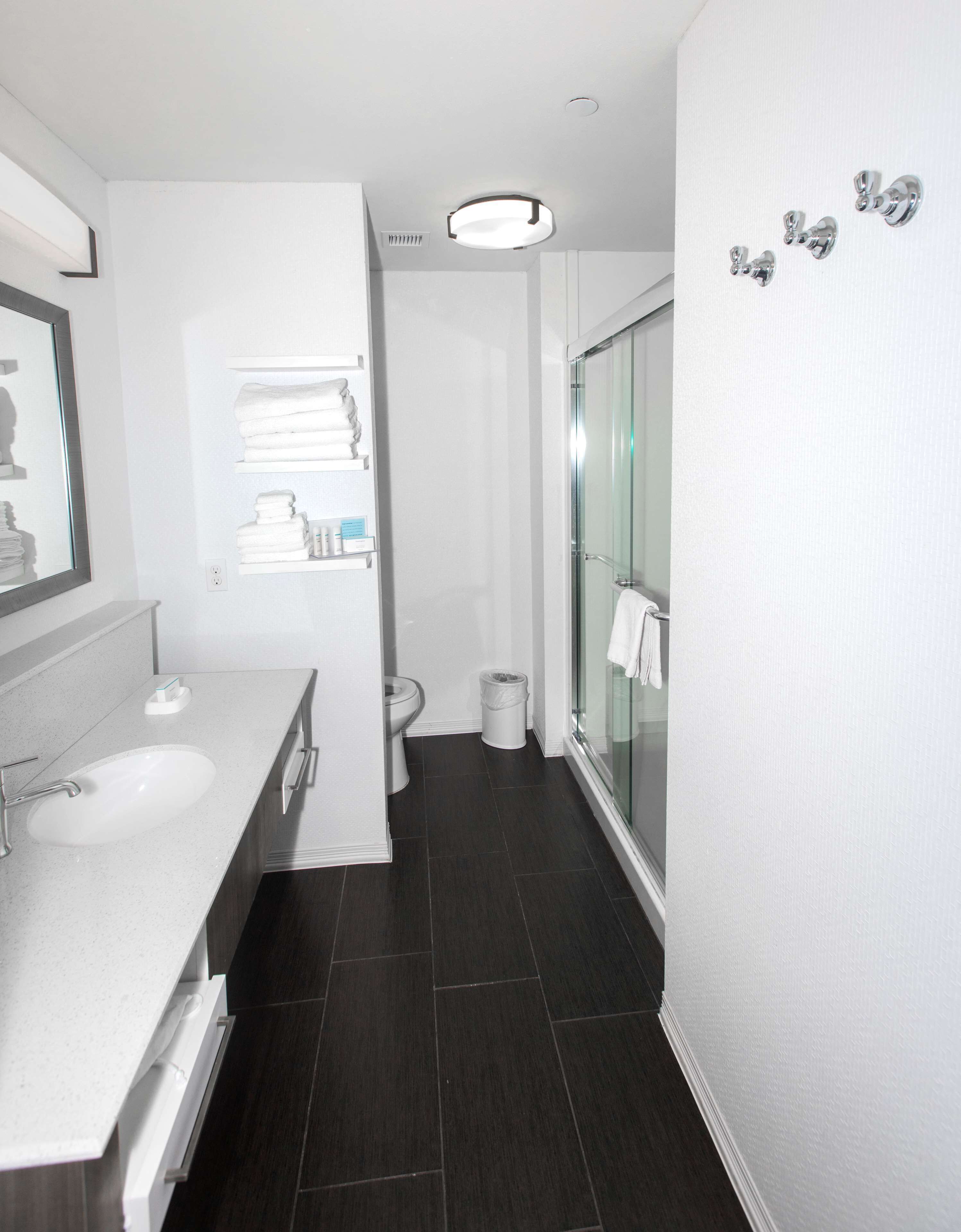 A modern bathroom with a double sink, toilet, and glass shower.