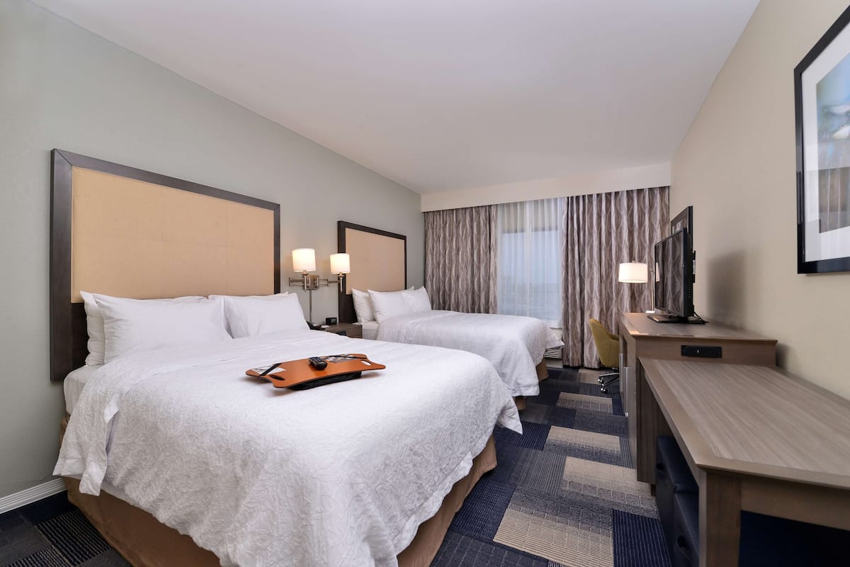 Ein Hotelzimmer mit zwei Betten, einem Schreibtisch und einem Fernseher.