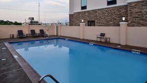 A swimming pool with lounge chairs, a poolside area, and a building with stone facade and windows. - Hampton Inn Broussard-Lafayette Area (Broussard)