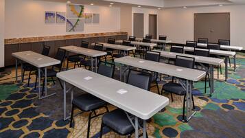 Una sala conferenze con diversi tavoli e sedie, un tappeto decorato e opere d'arte alle pareti.