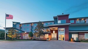 Un hôtel moderne, reconnaissable à son enseigne, qui s’étend sur plusieurs étages et dont l’entrée est bien éclairée.