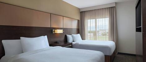 Une chambre d’hôtel avec deux lits, une grande fenêtre avec des rideaux, un téléviseur à écran plat et un minibar.