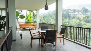 Een balkon met een tafel en stoelen, een bank en een hanglamp.