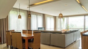 Een moderne woonkamer met een eethoek, grote ramen en een balkon.