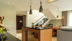 Een moderne keuken met een centraal eiland, houten kastjes en hanglampen.