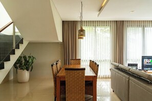 Uma sala de estar moderna com área de jantar, escada e televisão.