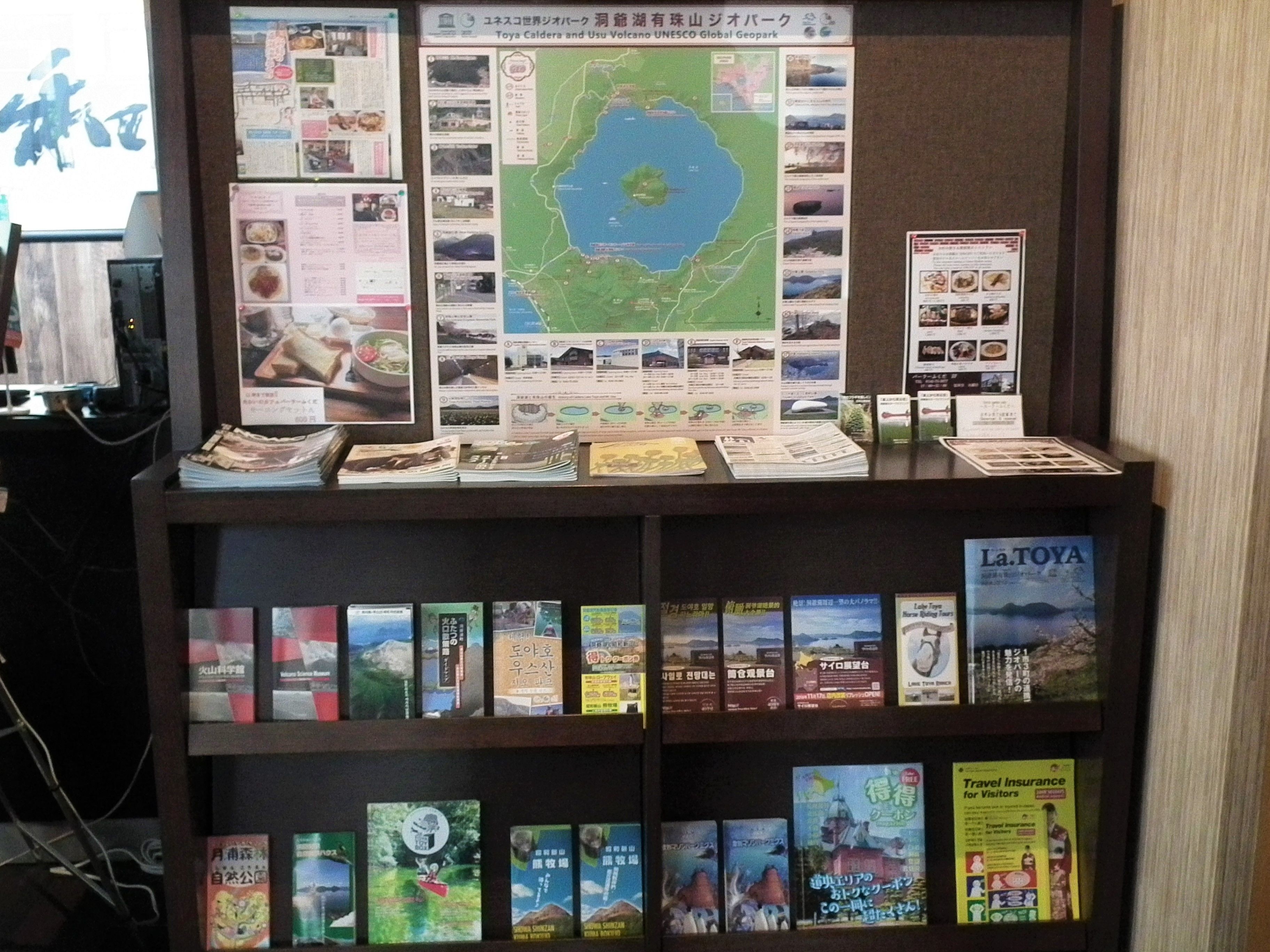 A display of travel books and maps, including a map of Toya Caldera and Usu Volcano UNESCO Global Geopark.