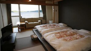 A room with two beds, a sofa, a TV, and a view of the sea. - Granvillage Toya Daiwa Ryokan Annex (Toyako)