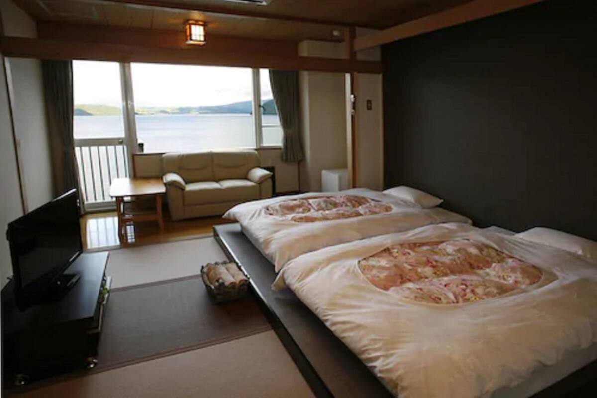 Une chambre avec deux lits, un canapé, une télévision et une vue sur la mer.