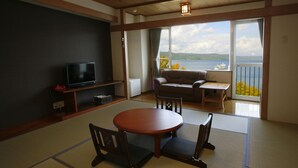 A traditional Japanese room with tatami flooring, a tatami mat table, a sofa, and a television on a low shelf. - Granvillage Toya Daiwa Ryokan Annex (Toyako)