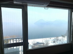 A room with a large window overlooking a snowy landscape and mountains. - Granvillage Toya Daiwa Ryokan Annex (Toyako)
