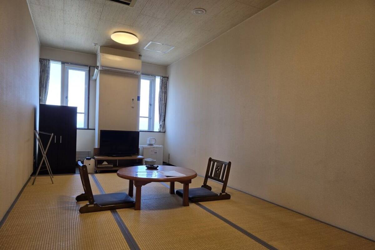 Une pièce avec des tatamis, une télévision, un bureau et une chaise.