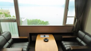 A room with a view of a body of water, a small table with a chair, and two sofas. - Granvillage Toya Daiwa Ryokan Annex (Toyako)