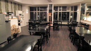 A dining area with multiple tables and chairs, a clock, and large windows. - Granvillage Toya Daiwa Ryokan Annex (Toyako)