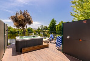 A wooden deck with a hot tub, outdoor seating, and a view of a lake. - Accent House Boutique Bed & Breakfast (Mapua)
