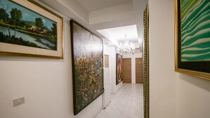 A hallway with framed artworks on the walls, a chandelier, and a tiled floor. - OYO 568 Art Hotel Hua Lamphong - Hostel (Bangkok)