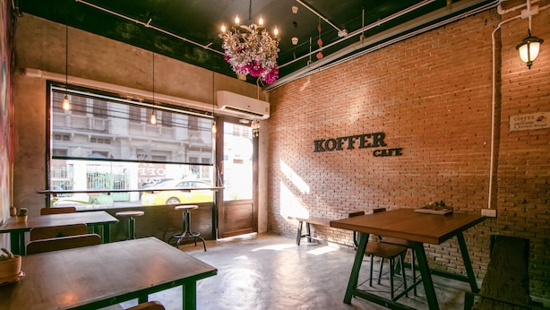 A cafe interior with brick walls, wooden tables, and hanging lights. - OYO 568 Art Hotel Hua Lamphong - Hostel (Bangkok)