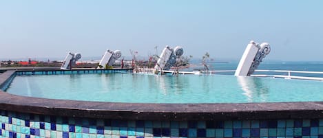 Een buitenzwembad, parasols voor strand/zwembad