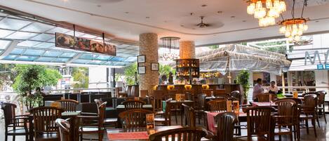 A spacious restaurant with wooden furniture, a bar area, and a view of the outdoors through large windows.