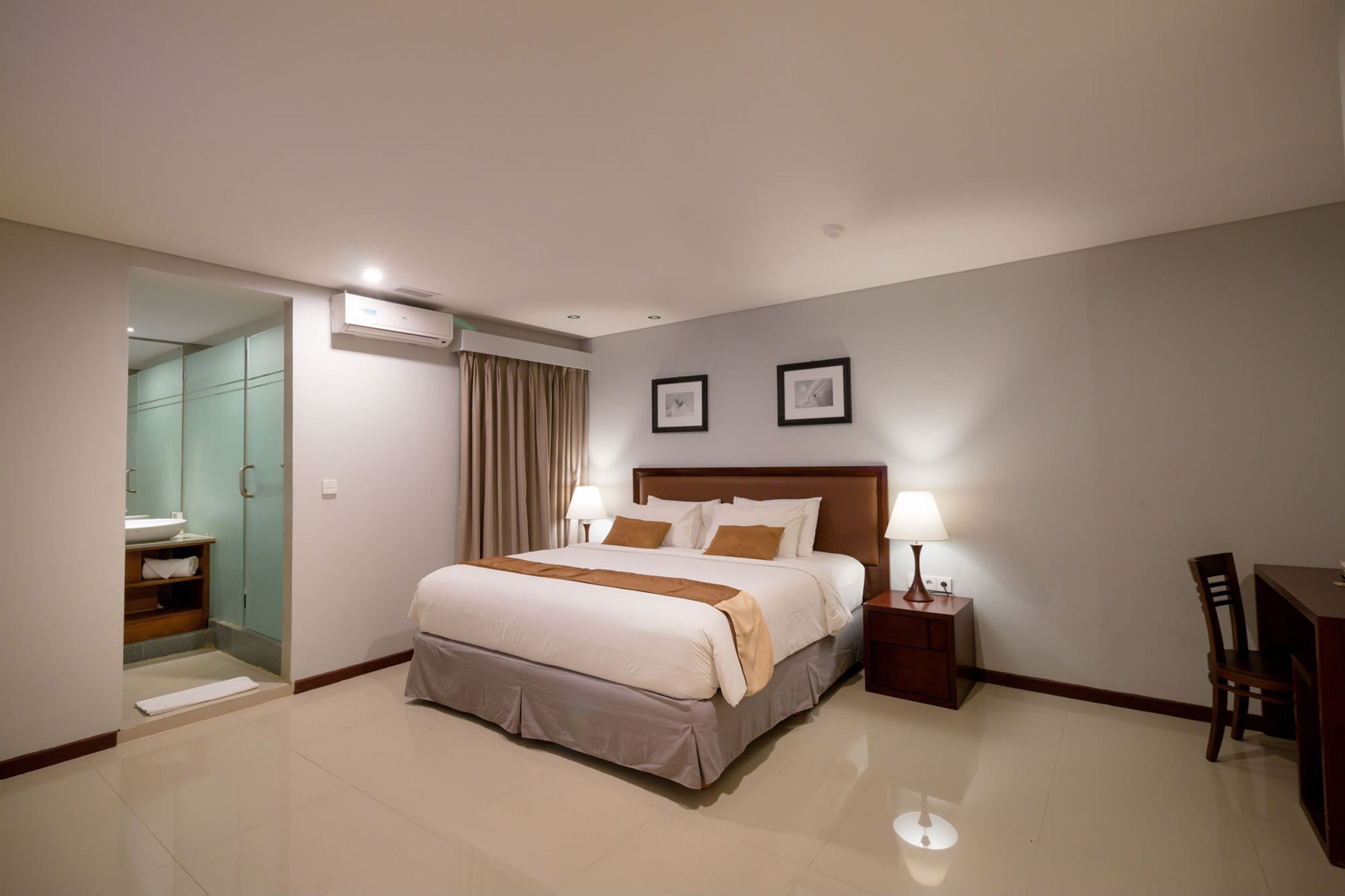 Een hotelkamer met een groot bed, bedlampen, een bureau en een stoel.