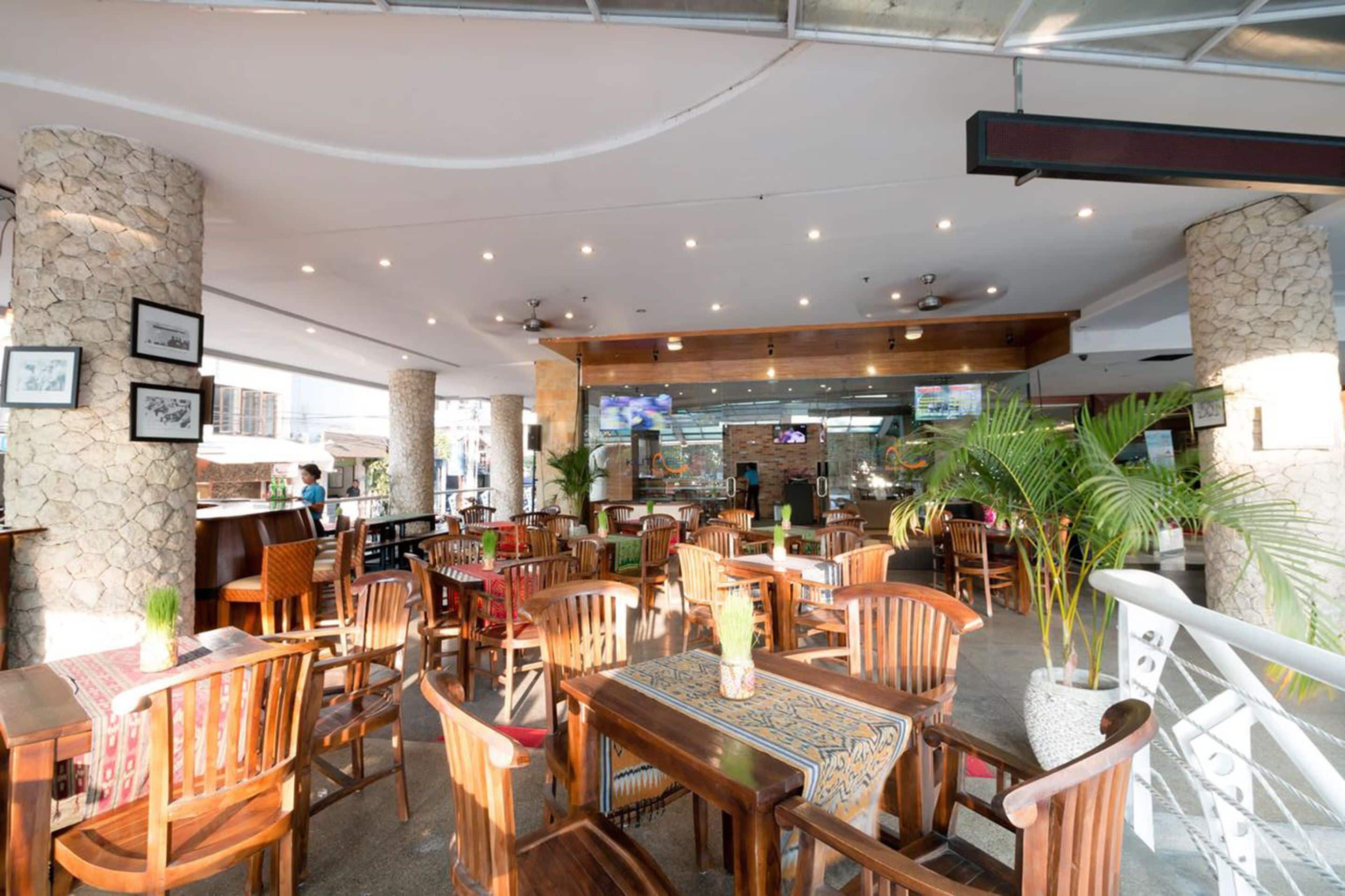 A spacious indoor dining area with wooden tables and chairs, stone pillars, and a counter with a menu display.