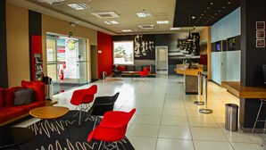 A modern lobby with red and black seating, a reception desk, and a large window with a view. - ibis Bacabal (Bacabal)