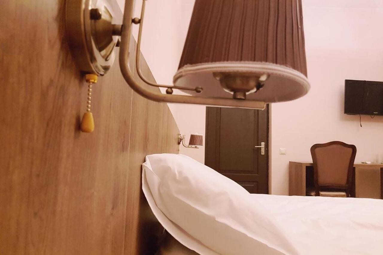 Ett hotellrum med en säng, ett skrivbord, en stol, en tv på väggen och en dörr.