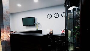 A reception area with a flat-screen TV, three wall clocks, and a glass display case with a flag. - Classic Hotel Tbilisi (Tbilisi)